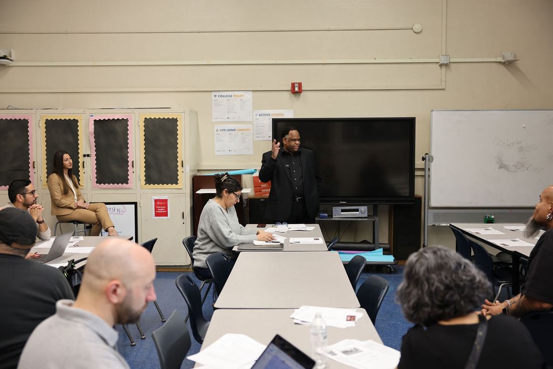 Michael Green speaking to a group of adults seated at tables in a Los Angeles school classroom